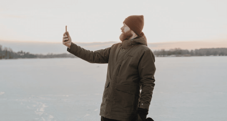 Man wearing a winter jacket holding a phone