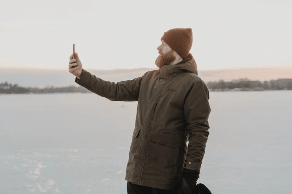 Man wearing a winter jacket holding a phone